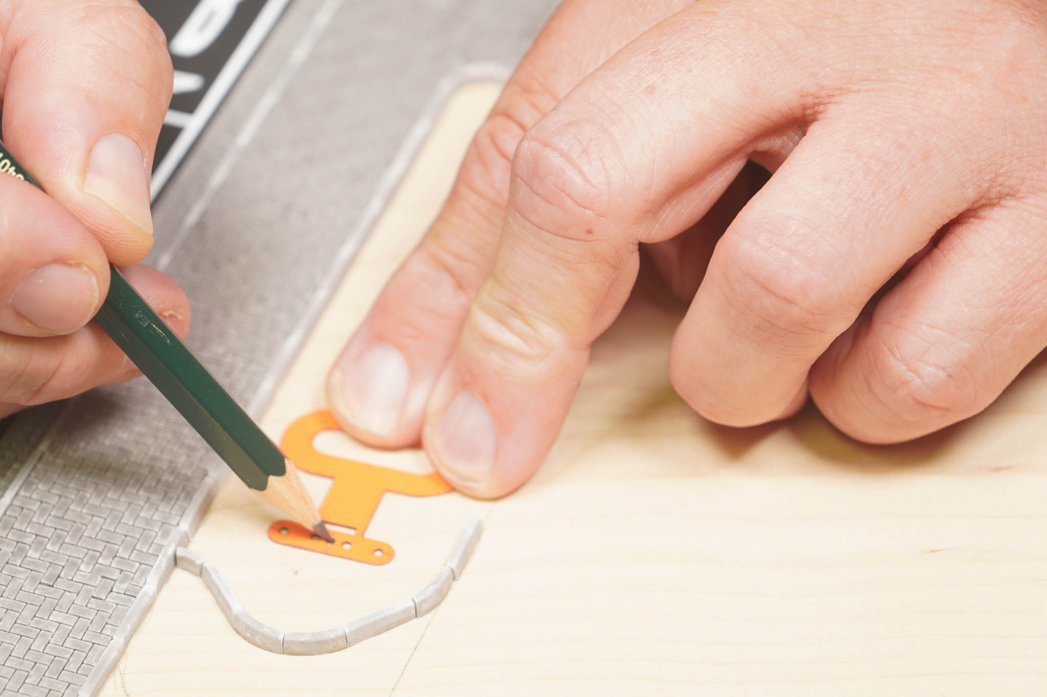 Mit einem Bleistift werden durch die kleinen Löcher der Anzeichenhilfe Punkte auf die Platte gezeichnet