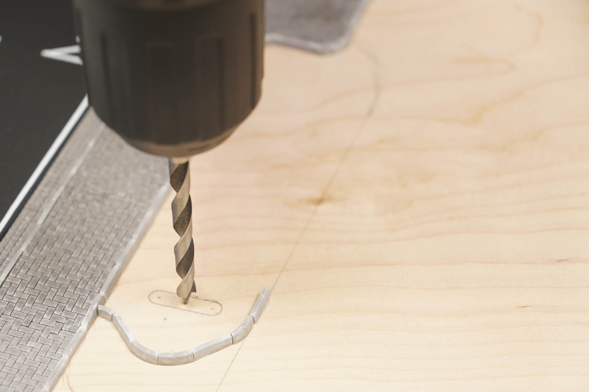 Ein 5-mm-Holzbohrer bohrt senkrecht in die angezeichnete Fläche auf der Grundplatte