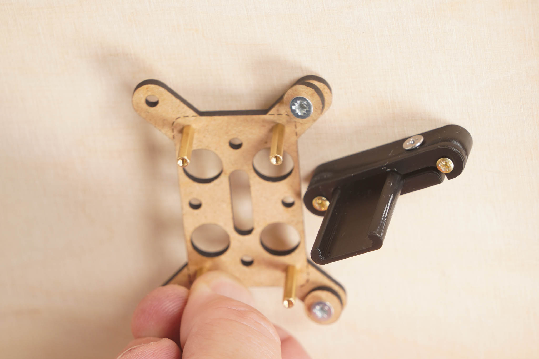 Zwei der vier Spanplattenschrauben sind bereits eingedreht und halten den Controller-Halter an der Platte